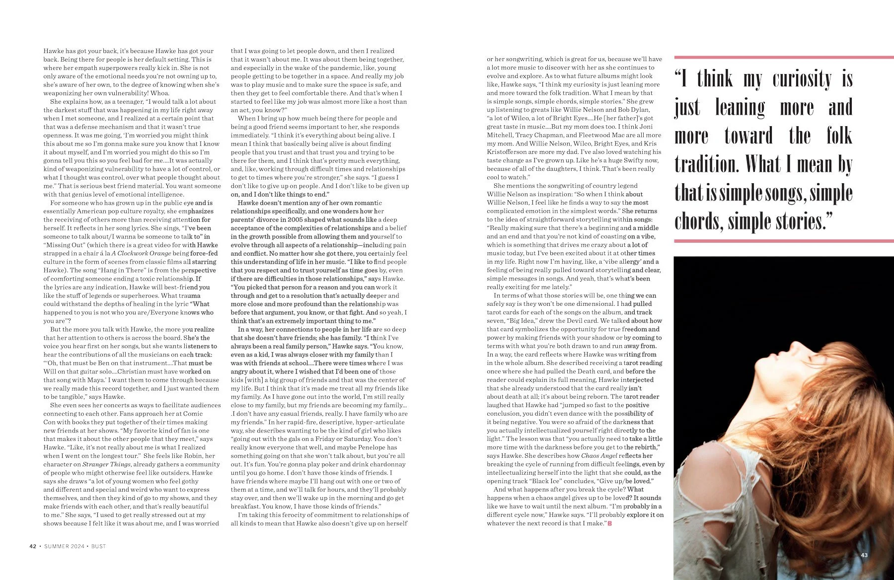 A woman with long, reddish hair, wearing a white distressed shirt, leaning forward with her head down and face not visible.