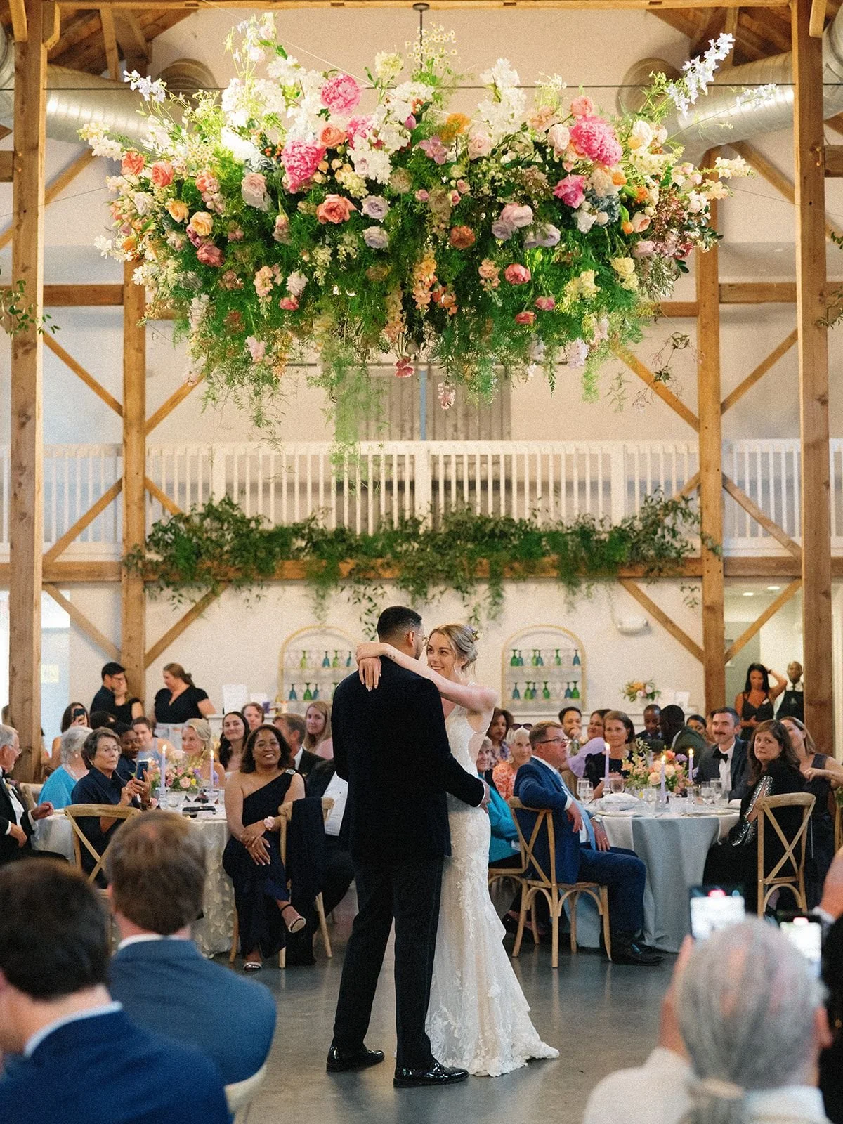 Colorful wedding flower hanging chandelier with vibrant blooms framing an indoor reception