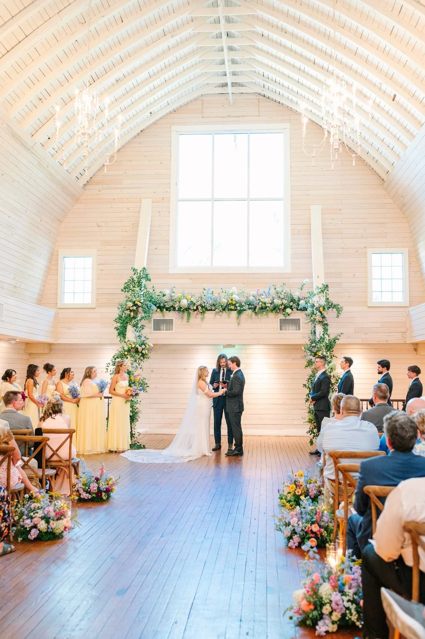 Colorful large floral arch designed inside of a historic barn venue