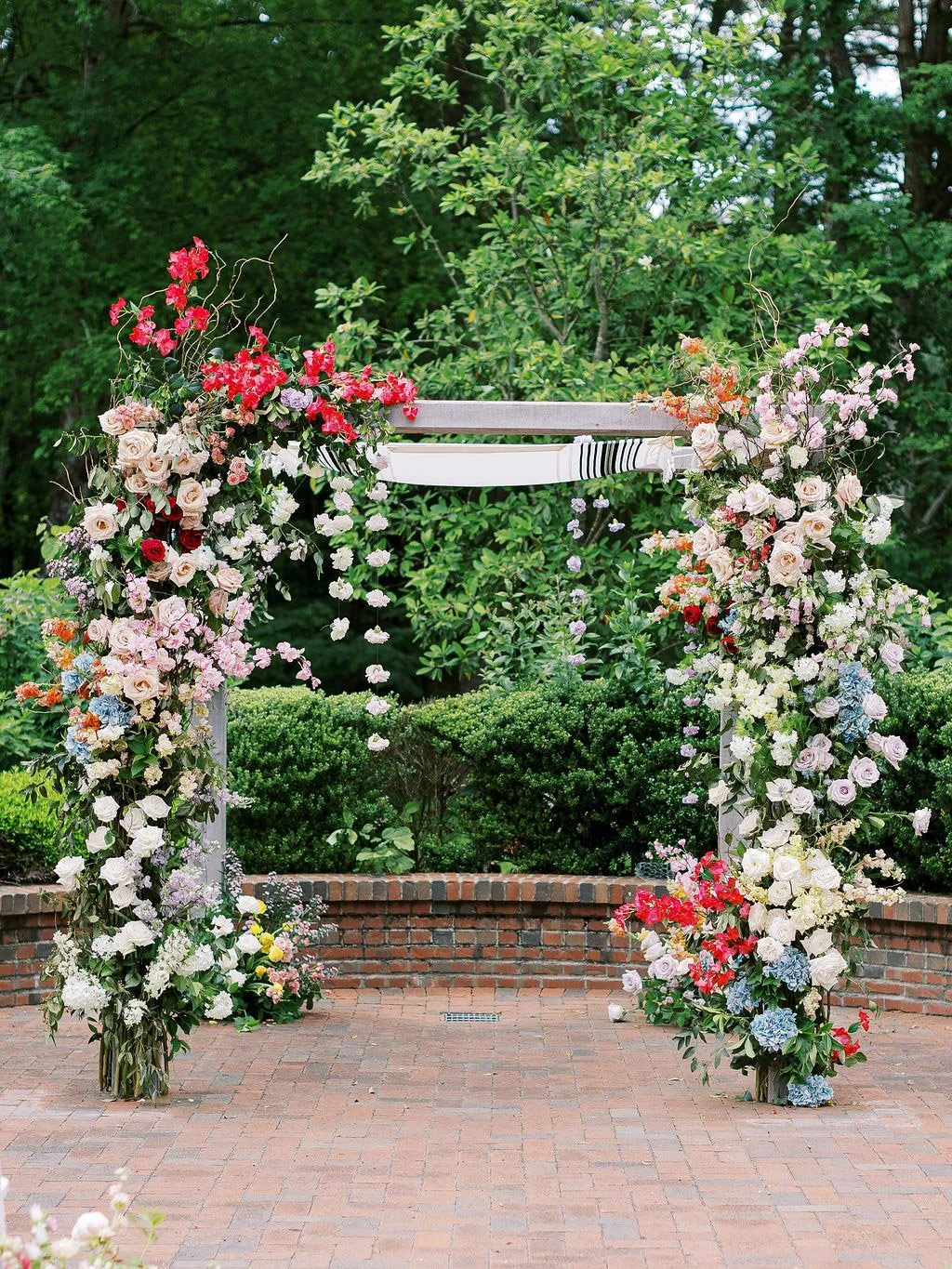 Colorful floral arch with garden roses and seasonal blooms set for a wedding ceremony at The Barn of Chapel Hill