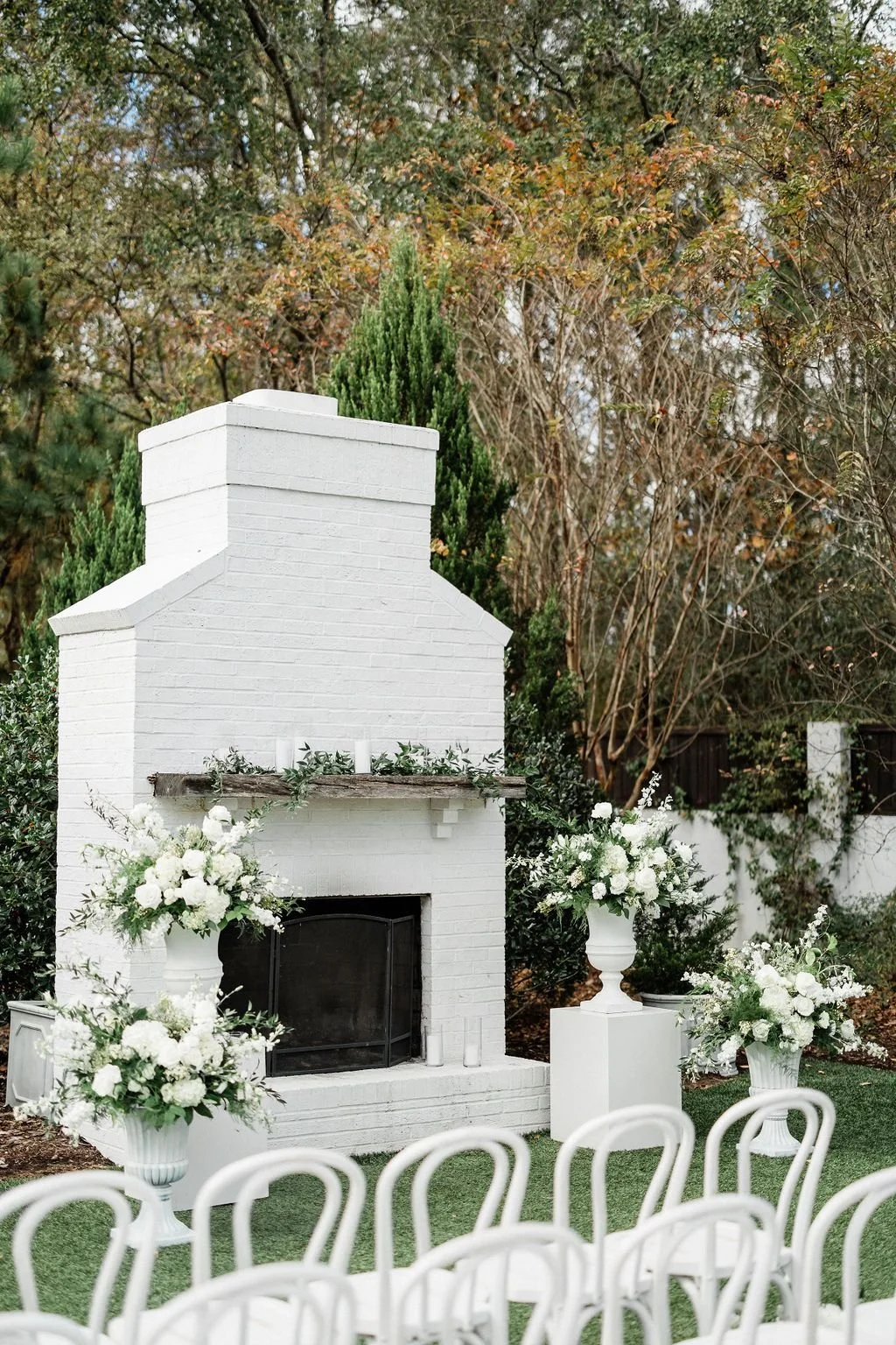 Fireplace wedding ceremony floral design with pedestal flower arrangements in tones of white and green