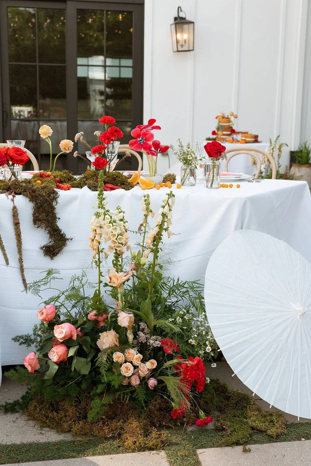 Romantic reception tablescape design with red and pastel flowers and moss