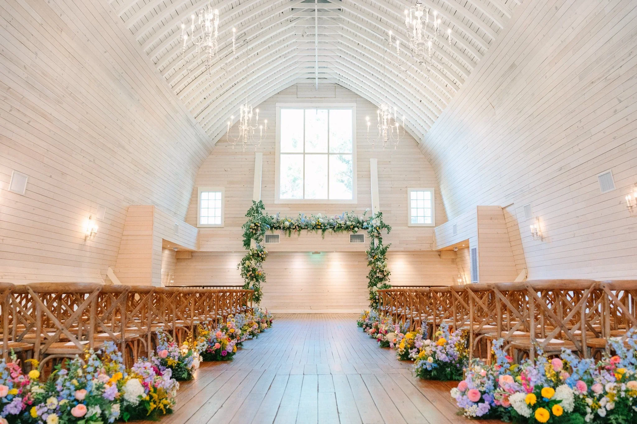 Colorful ceremony floral arch with lush meadow flowers along the aisle