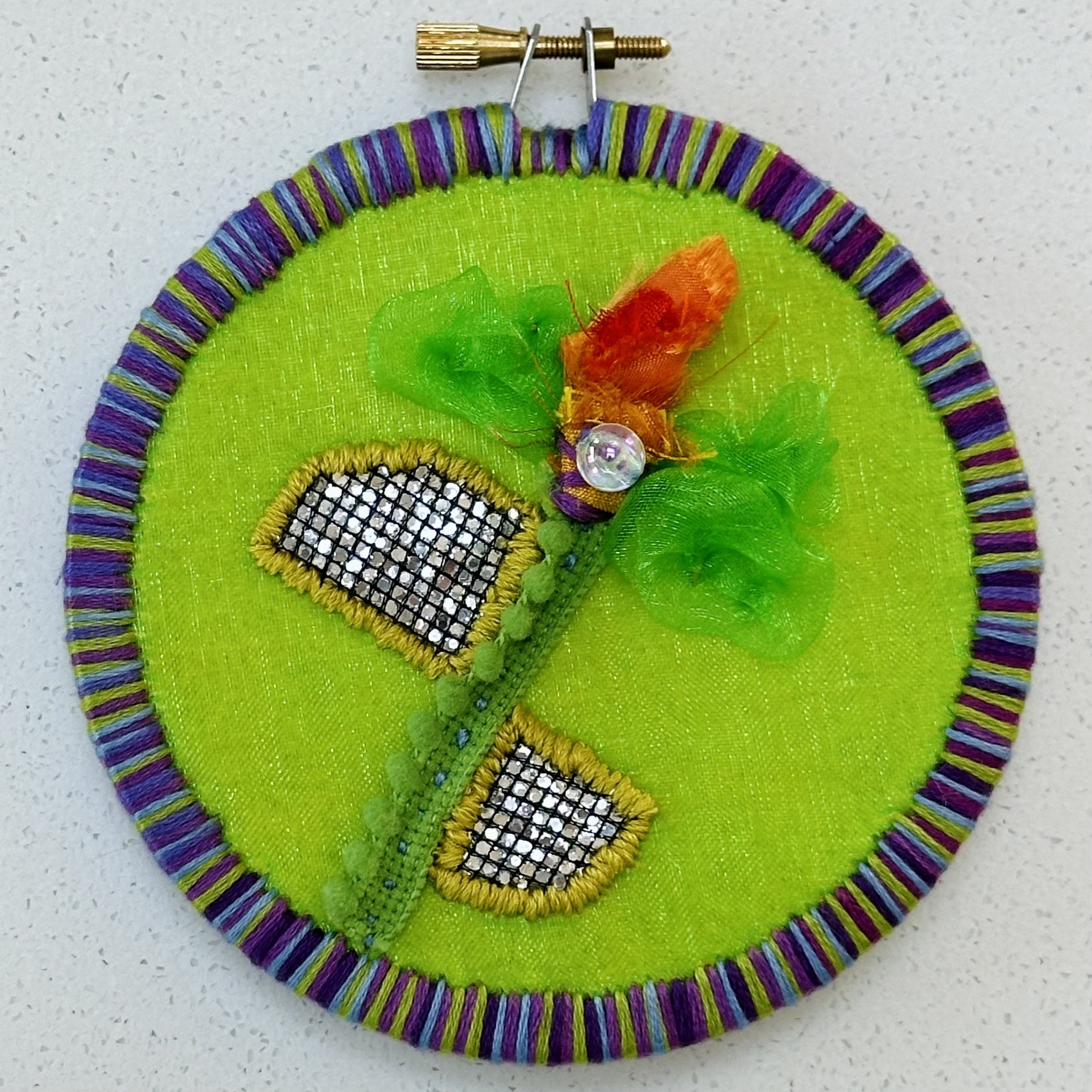 Spring (in spite of) (2024) embroidery thread, metallic material, trim, and bead on upcycled fabric 4.5" disc $