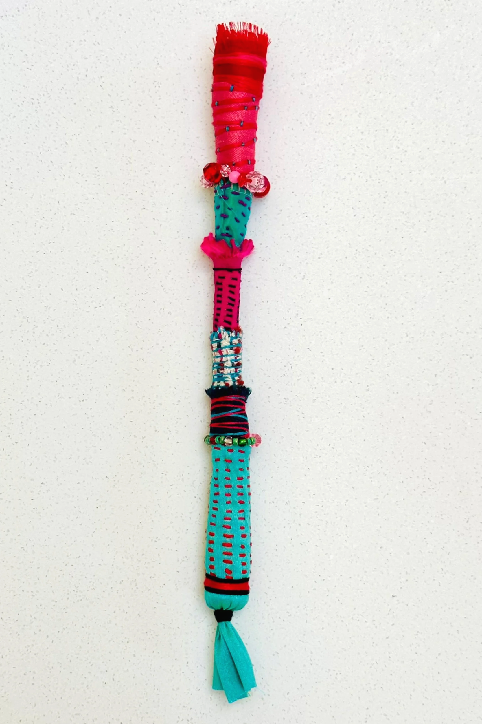 Little Relish   (2025)   felt, upcycled fabric, beads, Sashiko thread, embroidery thread   11" x 1.25" x 1.25"  