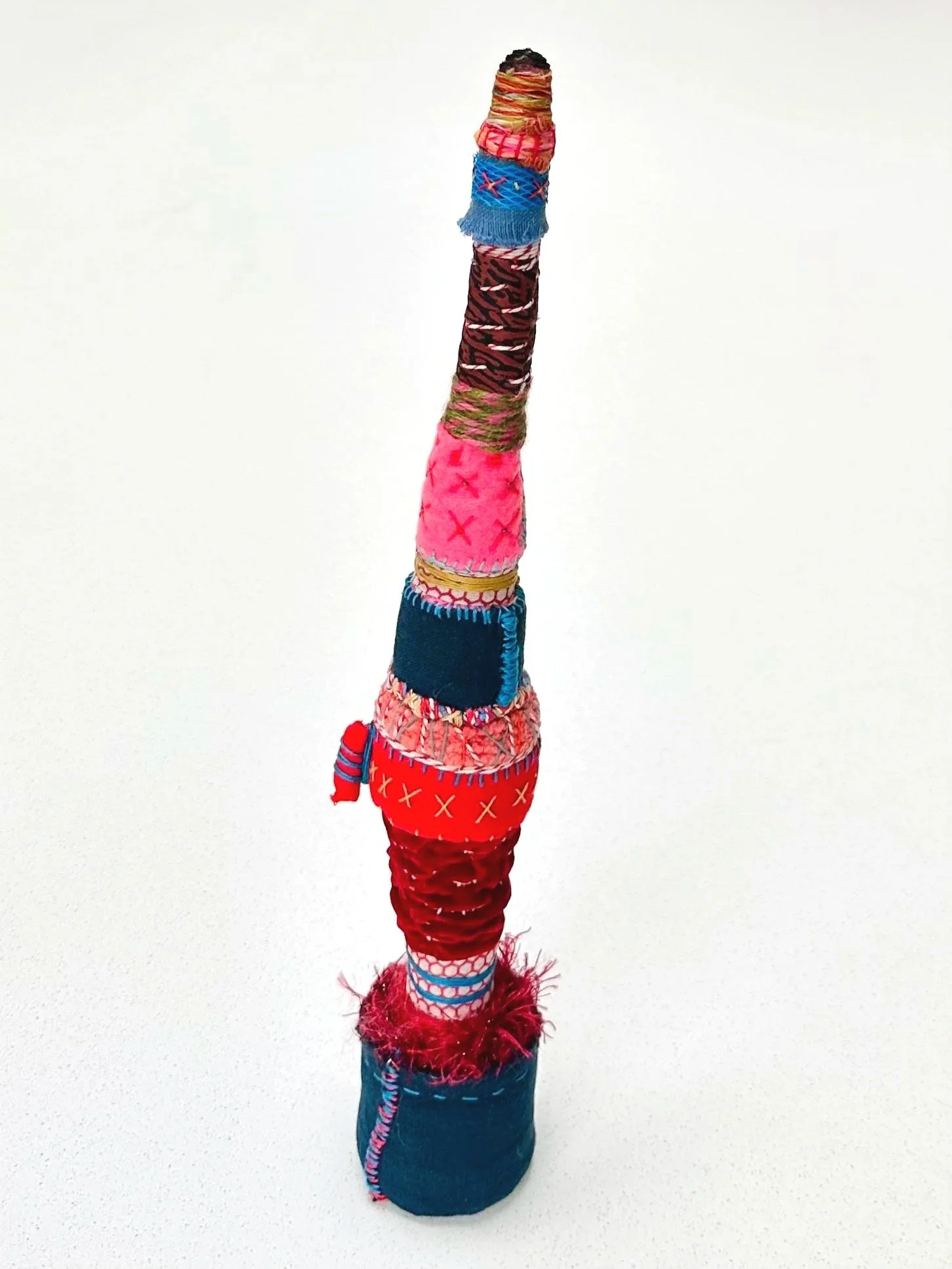  Trying to Keep the Layers in Line (While Scorched at the Top)  (freestanding)   (2025)   felt, upcycled fabric, Sashiko thread, embroidery thread, yarn, and candle flame   14" x 2" x 2"  $600