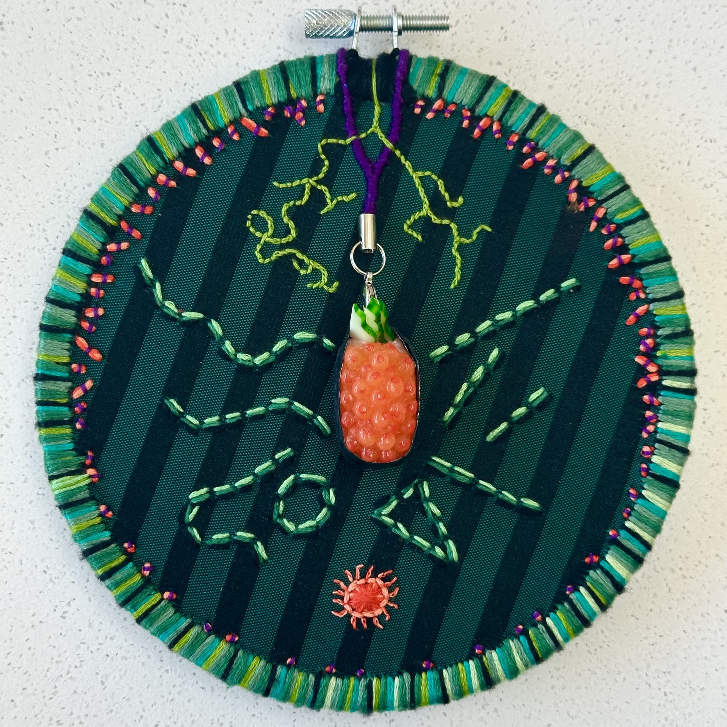 Not Making Sense (2024) embroidery thread on upcycled fabric with imitation sushi from Japan 6" disc $