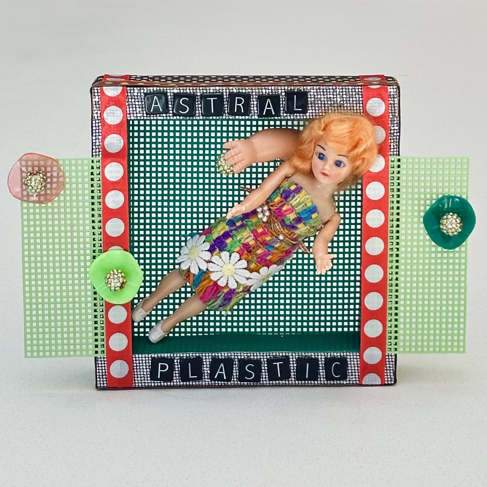 Astral Plastic (Simple Living) (2024) plastic doll, plastic grid, plastic letters, disco paper, ribbon, trim, fake pearls, plastic beads, wire, wood 7.5" x 11" $