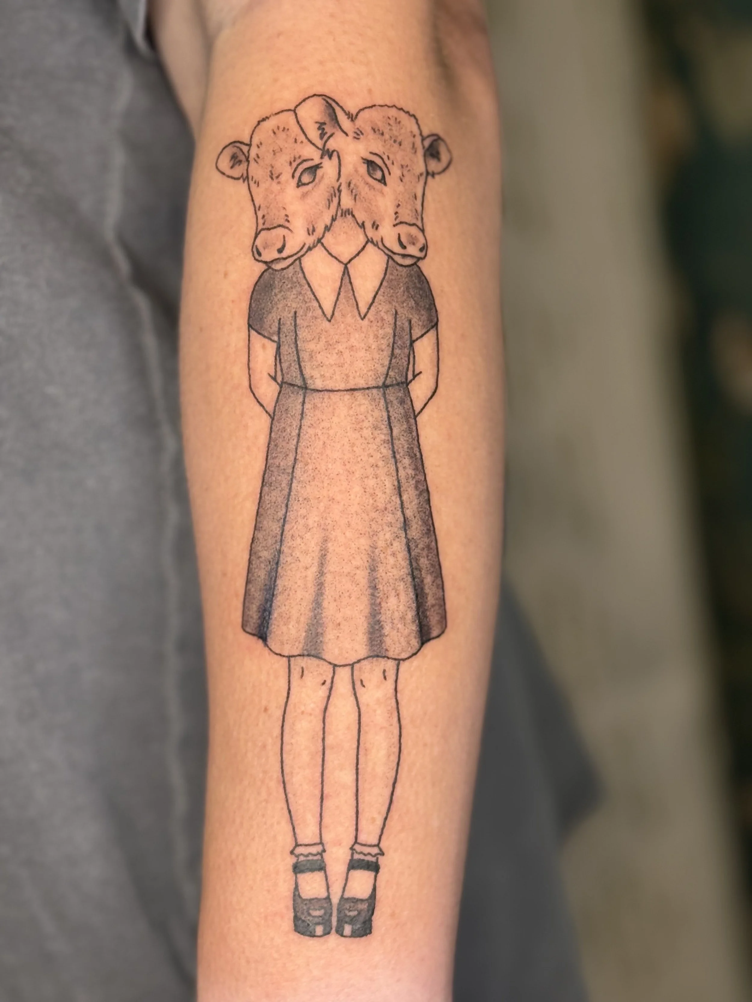 Tattoo of a girl with a dress and shoes, but her head is a dual-headed cow's head.