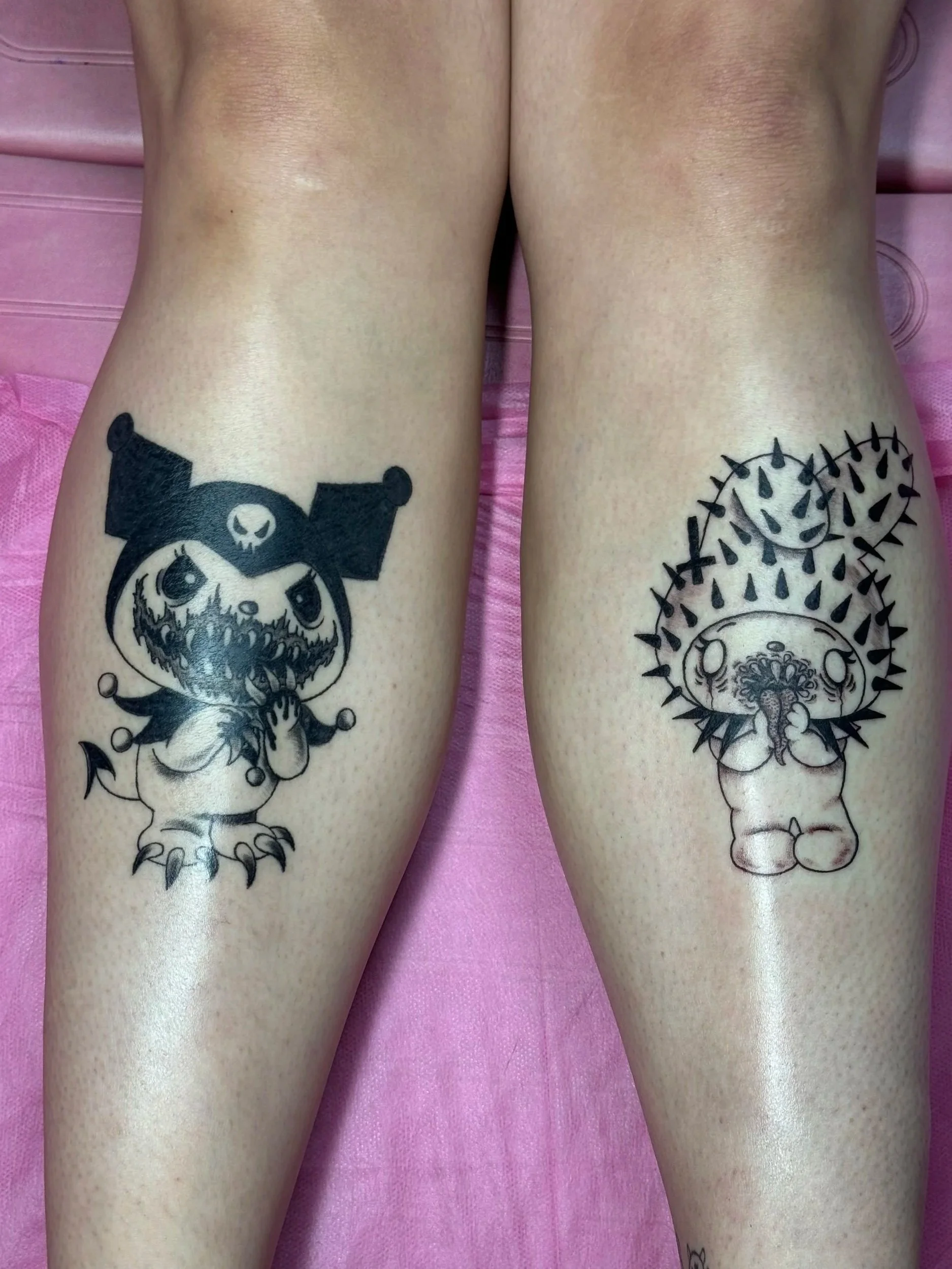 Two tattoos on the person's thighs, featuring cartoonish characters in black ink, one on each thigh.