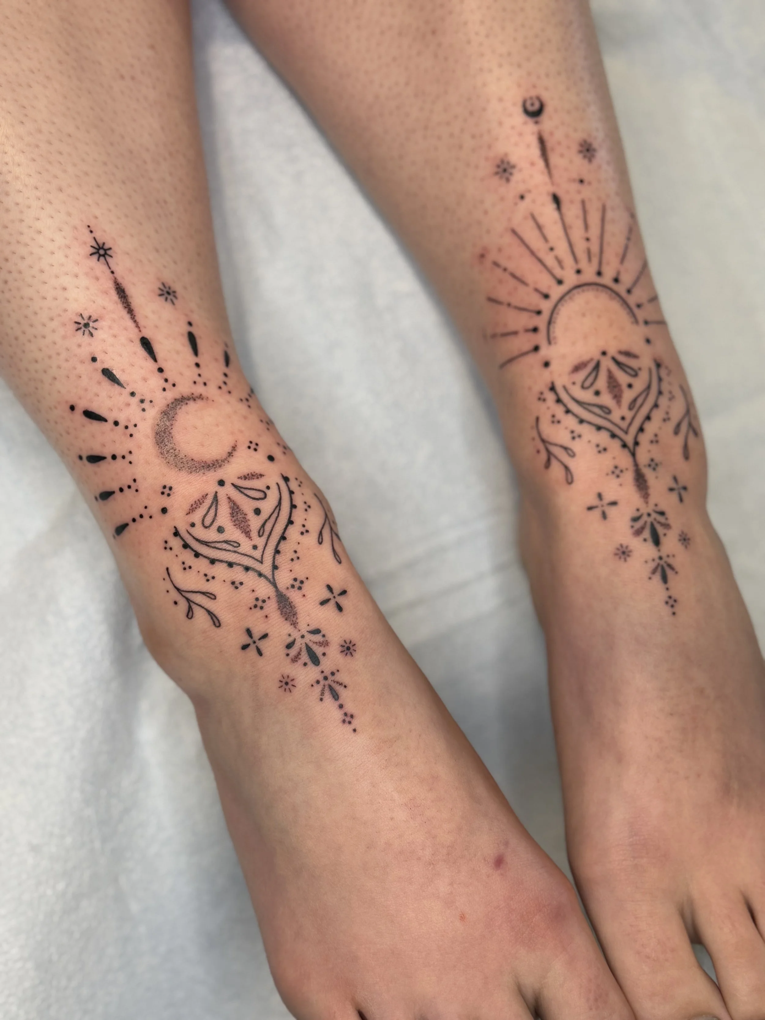 Tattoo of a moon, star, and geometric patterns on person's wrists.