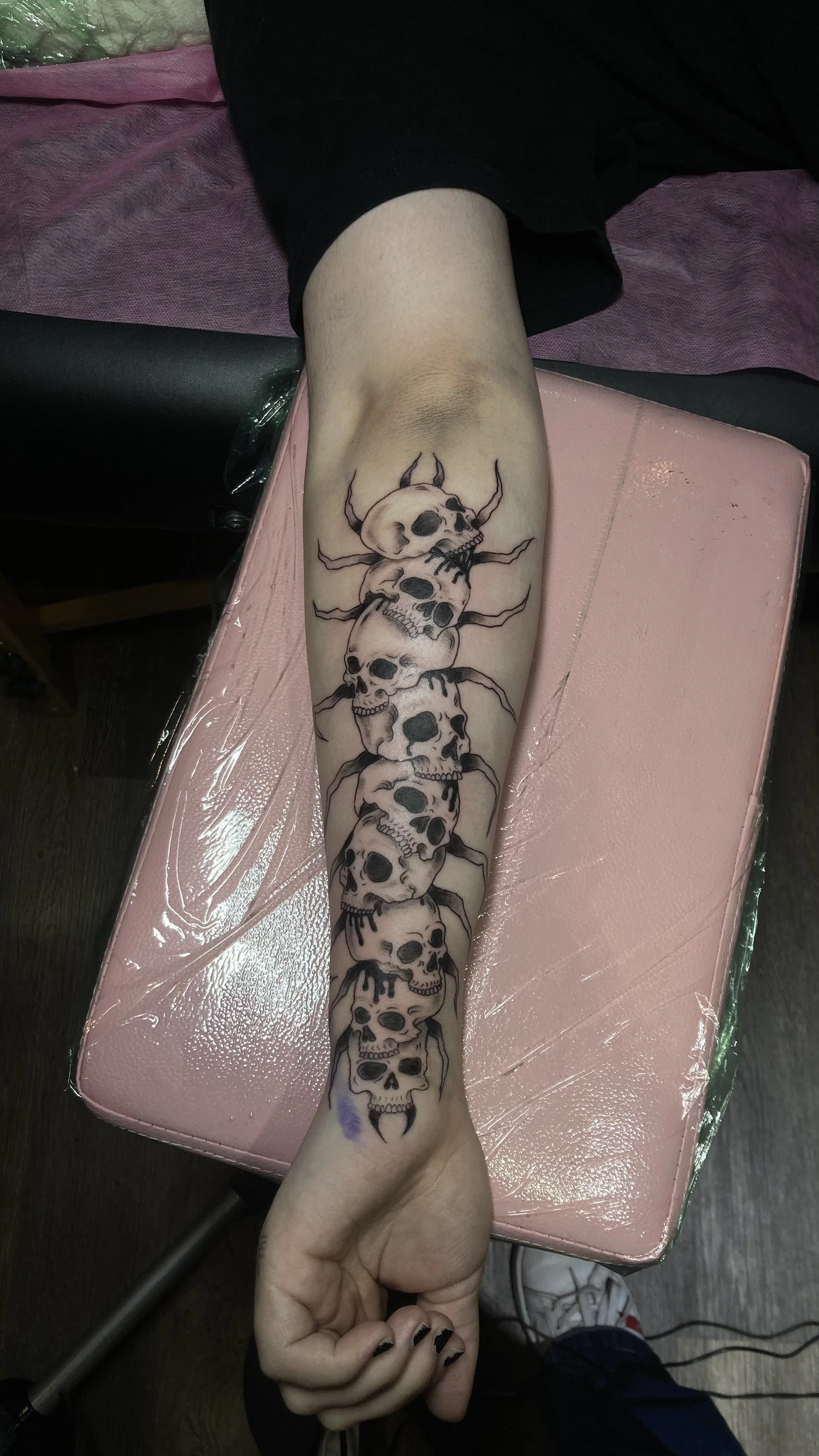 Tattoo of multiple black and white skulls stacked along a person's forearm.