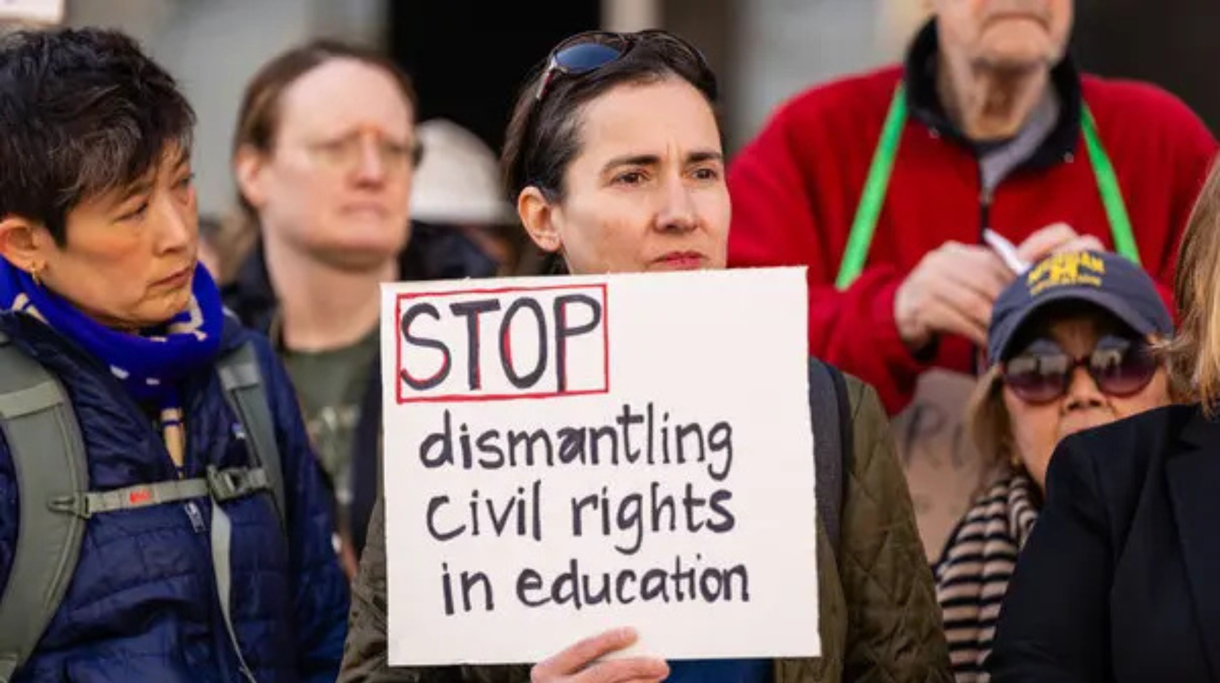 A person holds a sign that reads, "STOP dismantling civil rights in education"