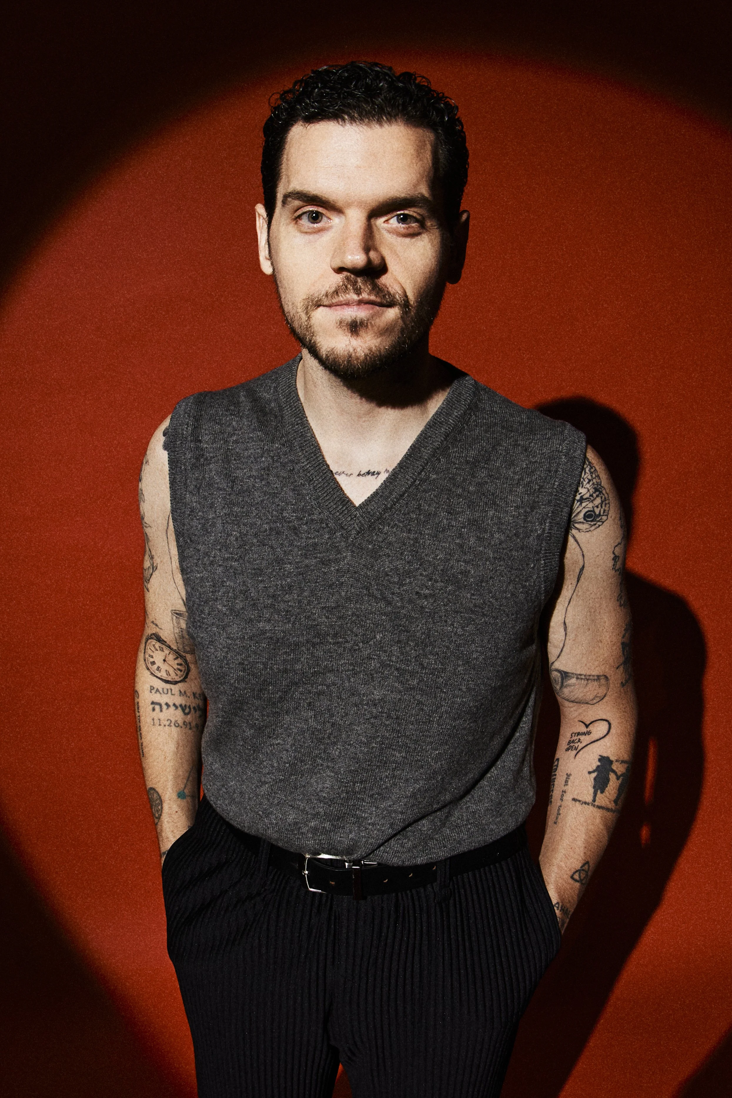 A white man with curly brown hair wearing a black polo shirt.