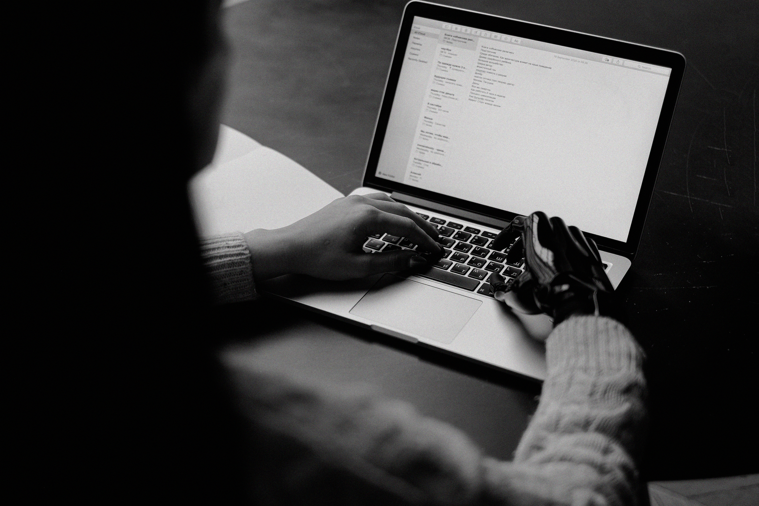 A person with a prosthetic right hand works on a laptop computer.