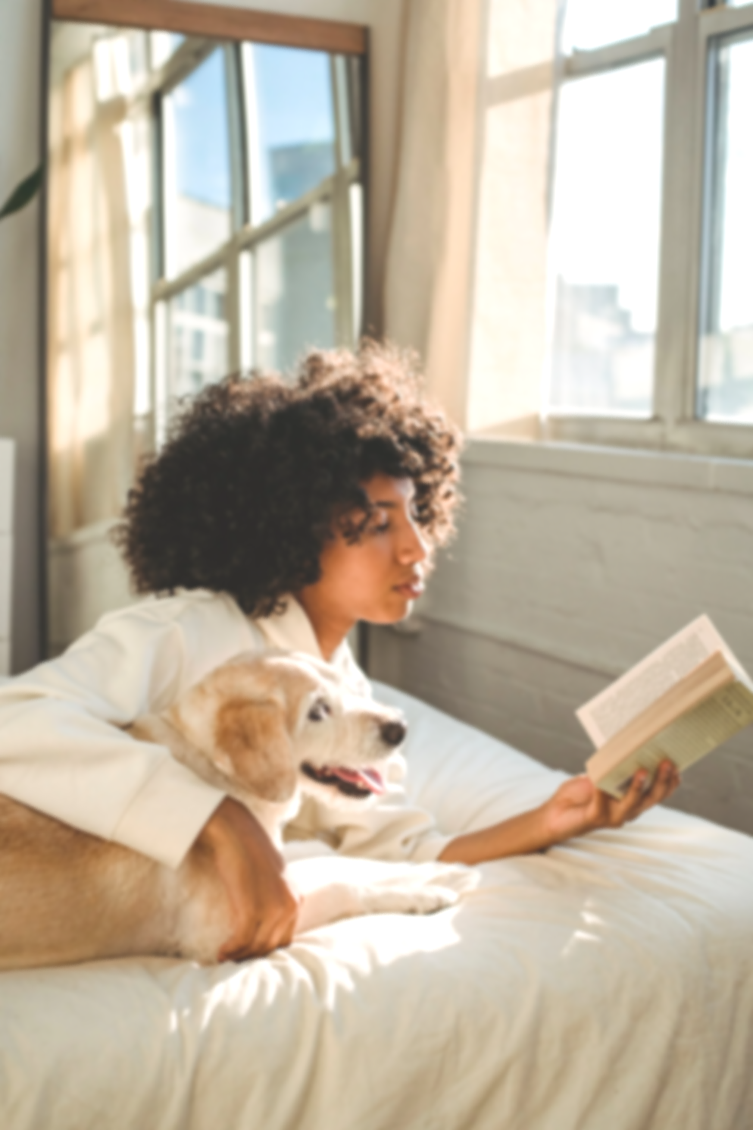 A relaxing scene of a woman with curly hair reading a book next to a dog, embodying a mindful space for nervous system regulation and holistic rest at Healju Hub.