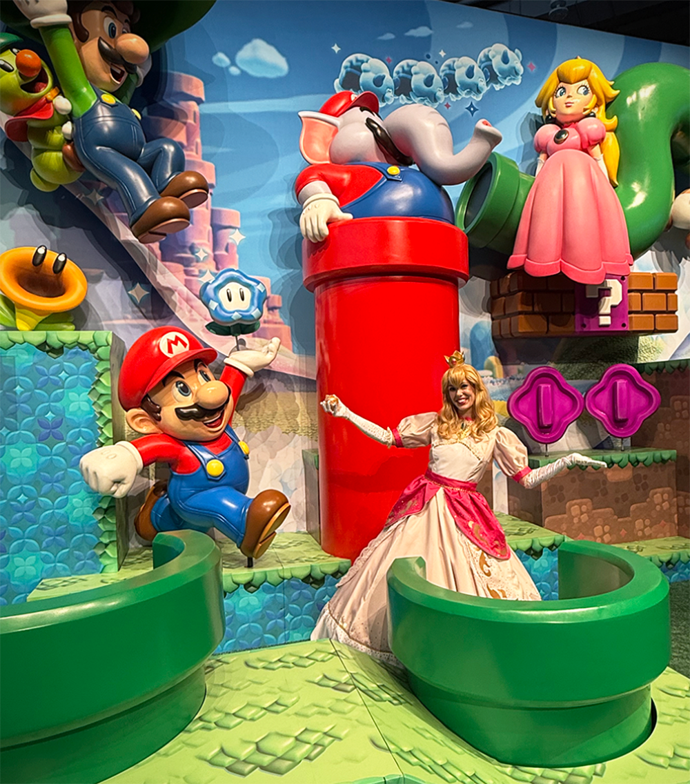 Princess Peach at the Nintendo Booth smiling behind a green pipe with a statue of Princess Peach behind her, shot at PAX East 2026