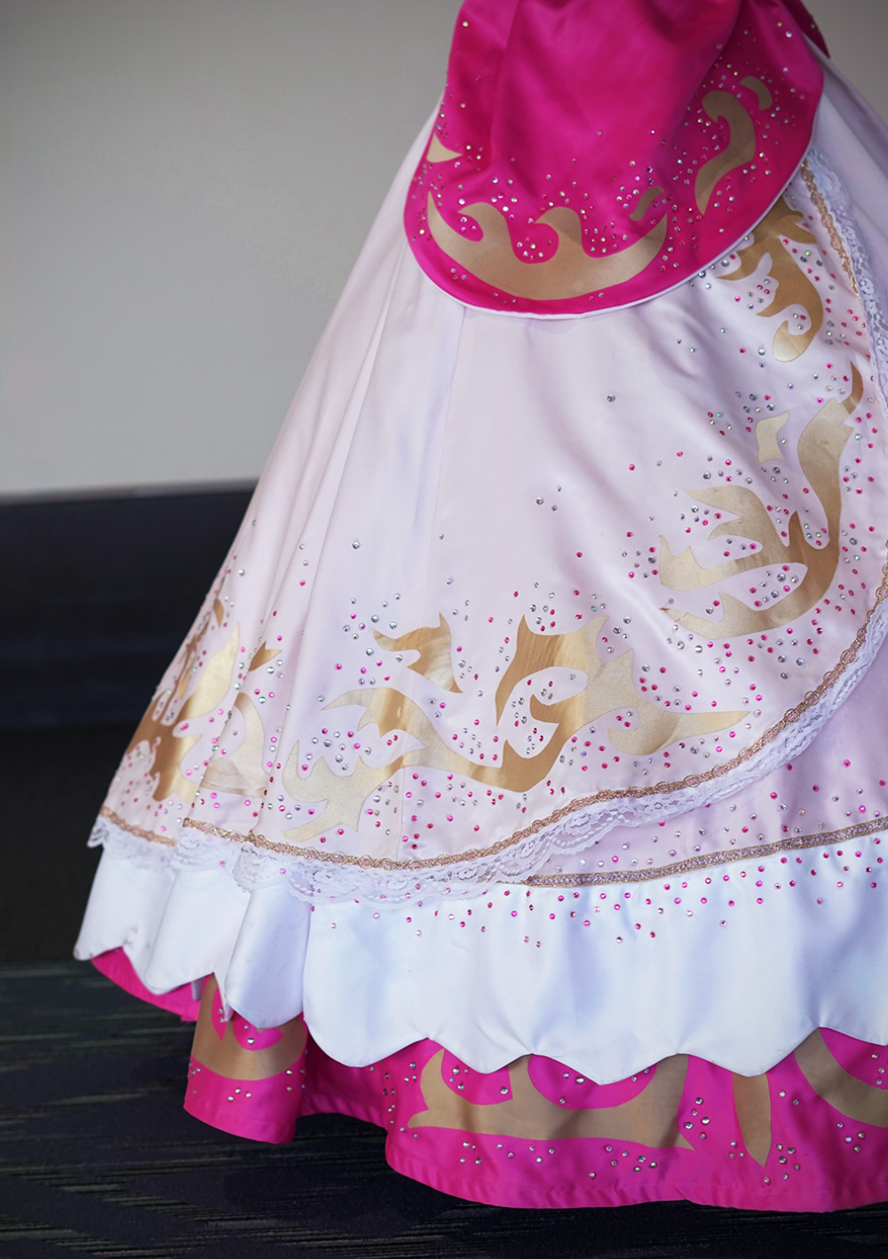 Princess Peach's skirts, shot from the waist down, highlighting gold details of the costume and thousands of rhinestones against a plain background, shot at PAX East 2026.