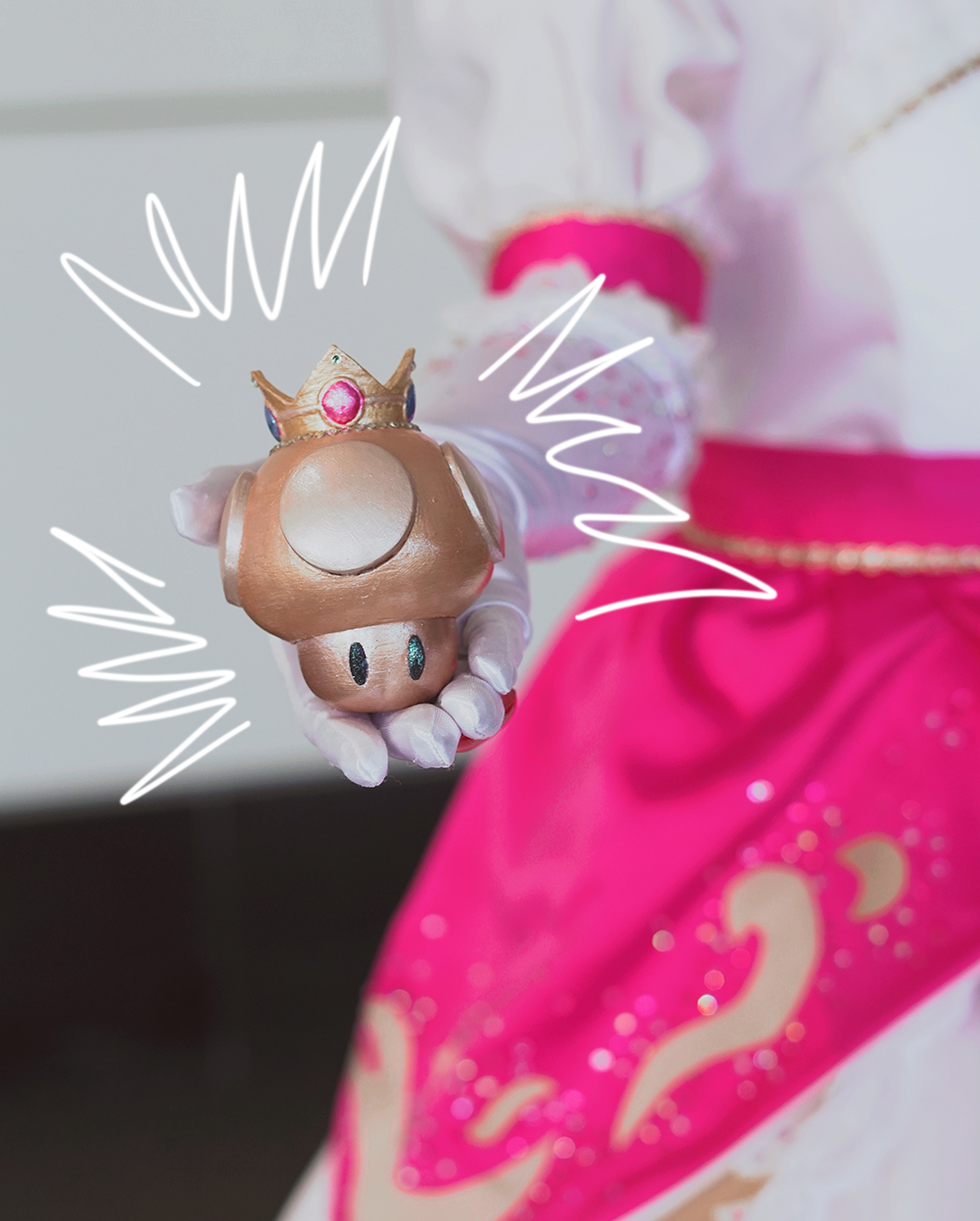Close-up of a 3-d printed gold mushroom with the vibrant pink Princess Peach costume in the background, at PAX East 2026;