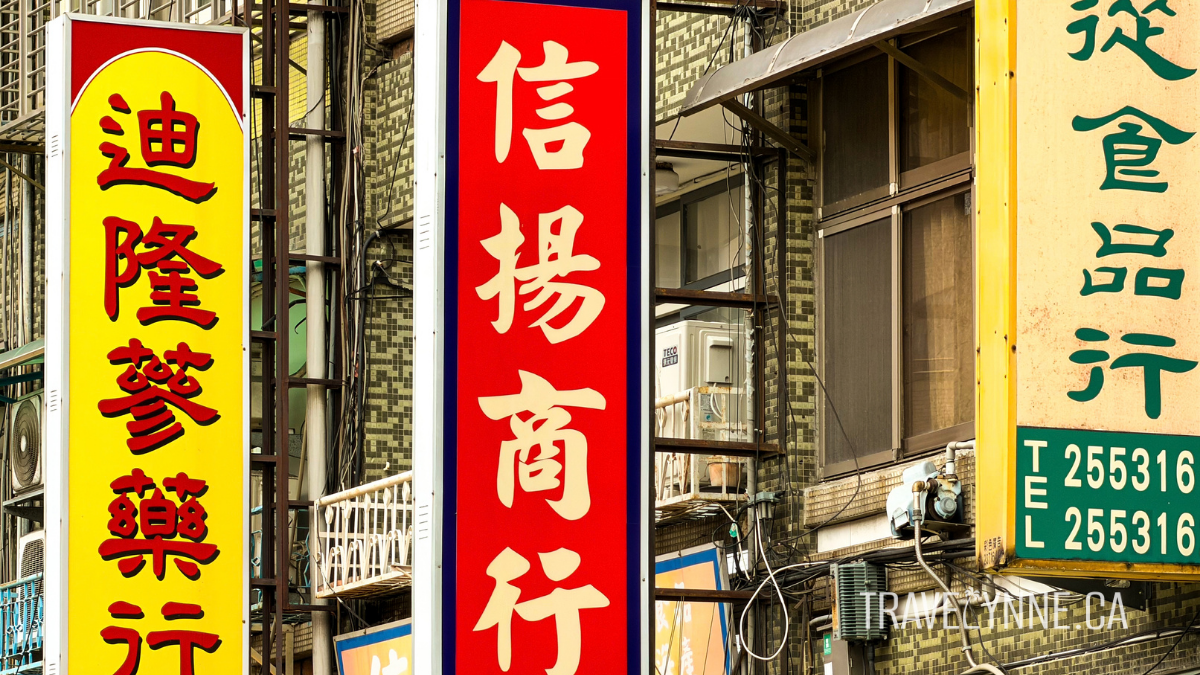 Bright coloured Chinese-language signs hang off the sides of buildings in Taipei