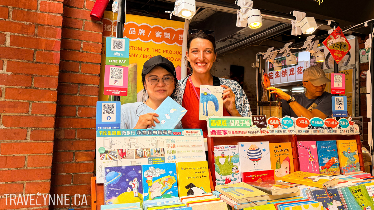 Lynne and a bookshop worker pose with their hand-stitched and designed notebooks in Dihua Street, Taipei
