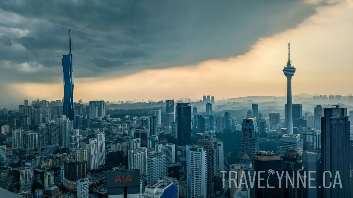 A moody KL skyline with dramatic grey clouds and the standout buildings of Merdeka 118 and KL Tower