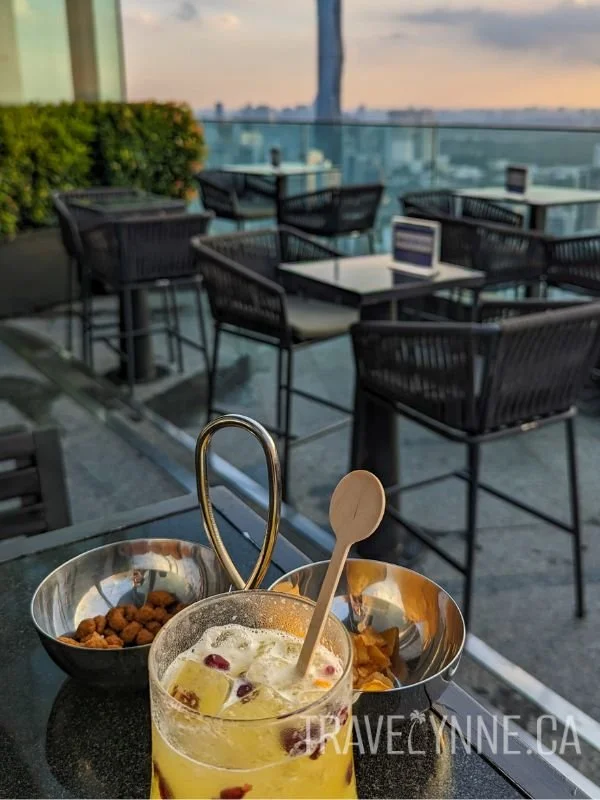 View from a tall table outside on the Vertigo rooftop, with a cityscape in the distance.
