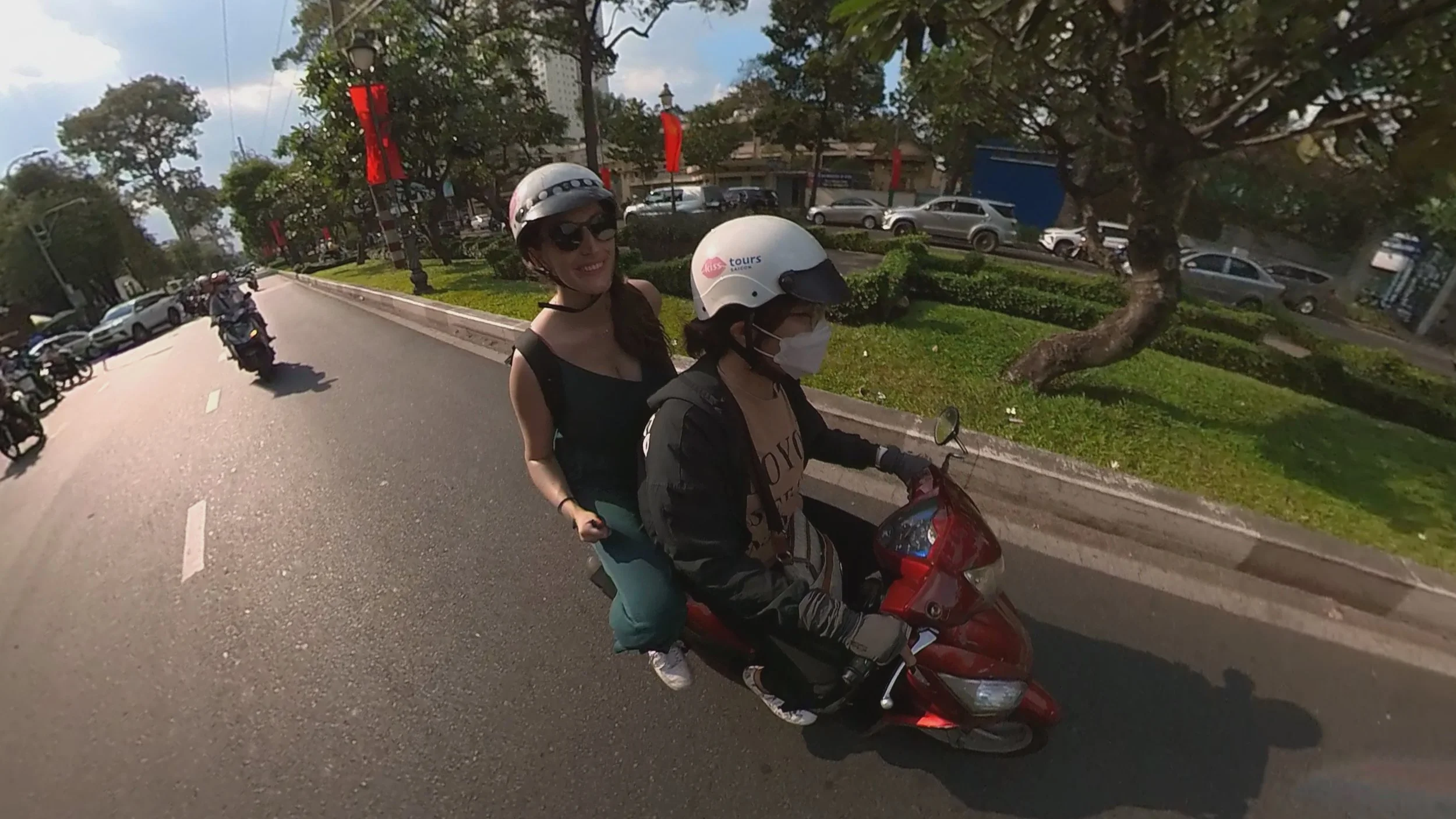 Lynne rides on the back of a red scooter with a local driver on the streets of Ho Chi Min City in Vietnam during a city tour