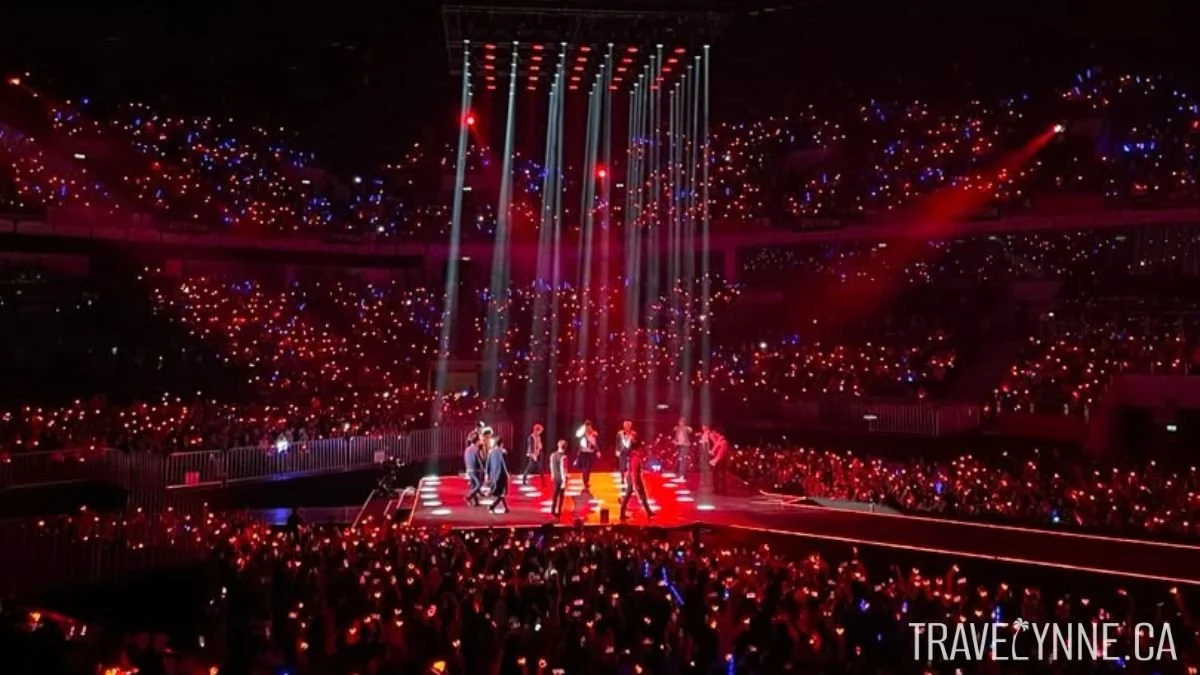 Super Junior perform in Axiata Arena (now Unifi Arena) in Kuala Lumpur, surrounded by red lights on attendees bracelets in the stadium around them