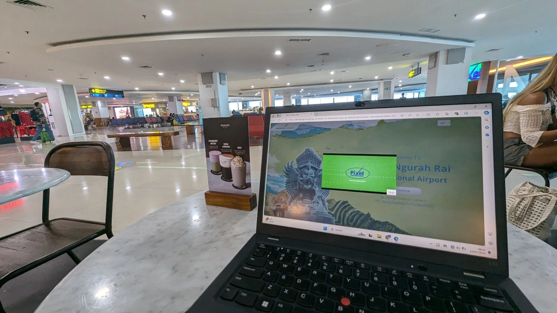 tables, a restaurant and gate with seating inside Bali's international airport