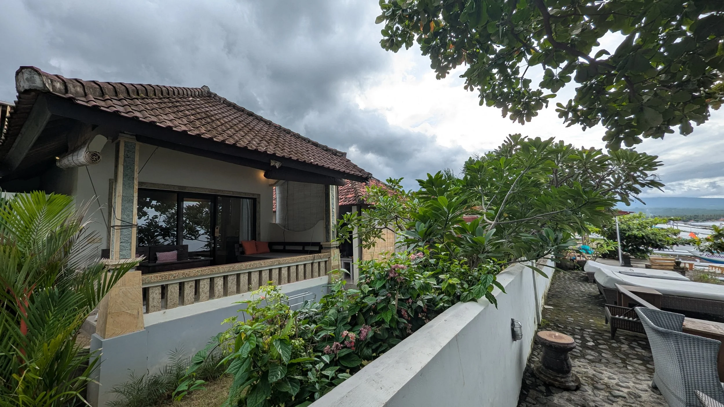 A beachfront bungalow in Amed with a big balcony overlooking the sea, and loungers on the beach ahead