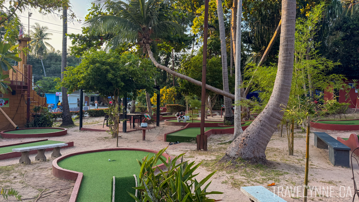 Several mini putt holes can be seen at a course in Koh Tao, dotted with palm trees.