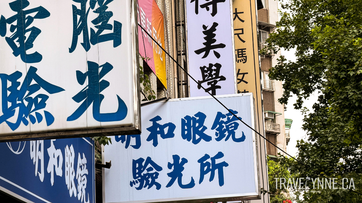 Blue, white and black signage hangs off the side of a building in Taipei