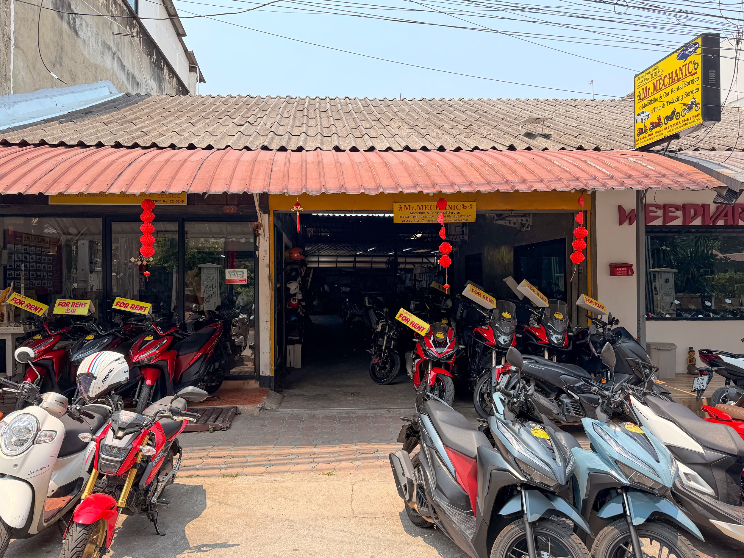 Several scooters are parked in front of Mr Mechanic rental shop in Chiang Mai, Thailand