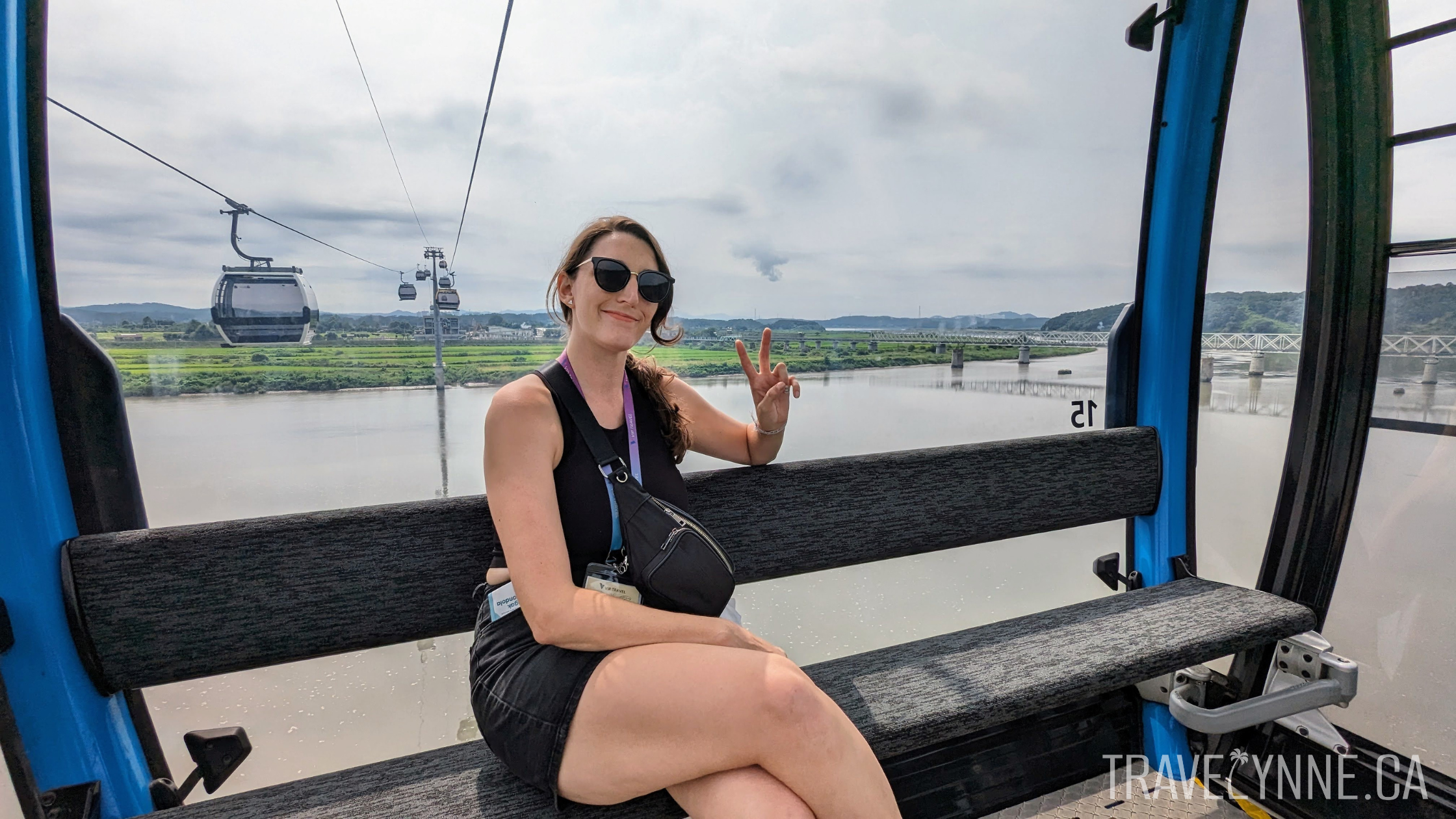 Lynne gives a peace sign with her hand while sitting on the Imjingak Peace Gondola over the Imjin River in the DMZ.