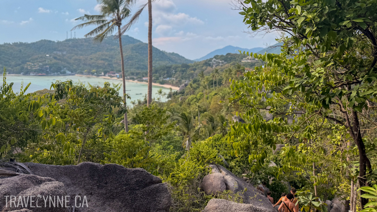 The view during the early descent from the John-Suwan Viewpoint, with large rocks on the trail and a turquoise bay in the horizon