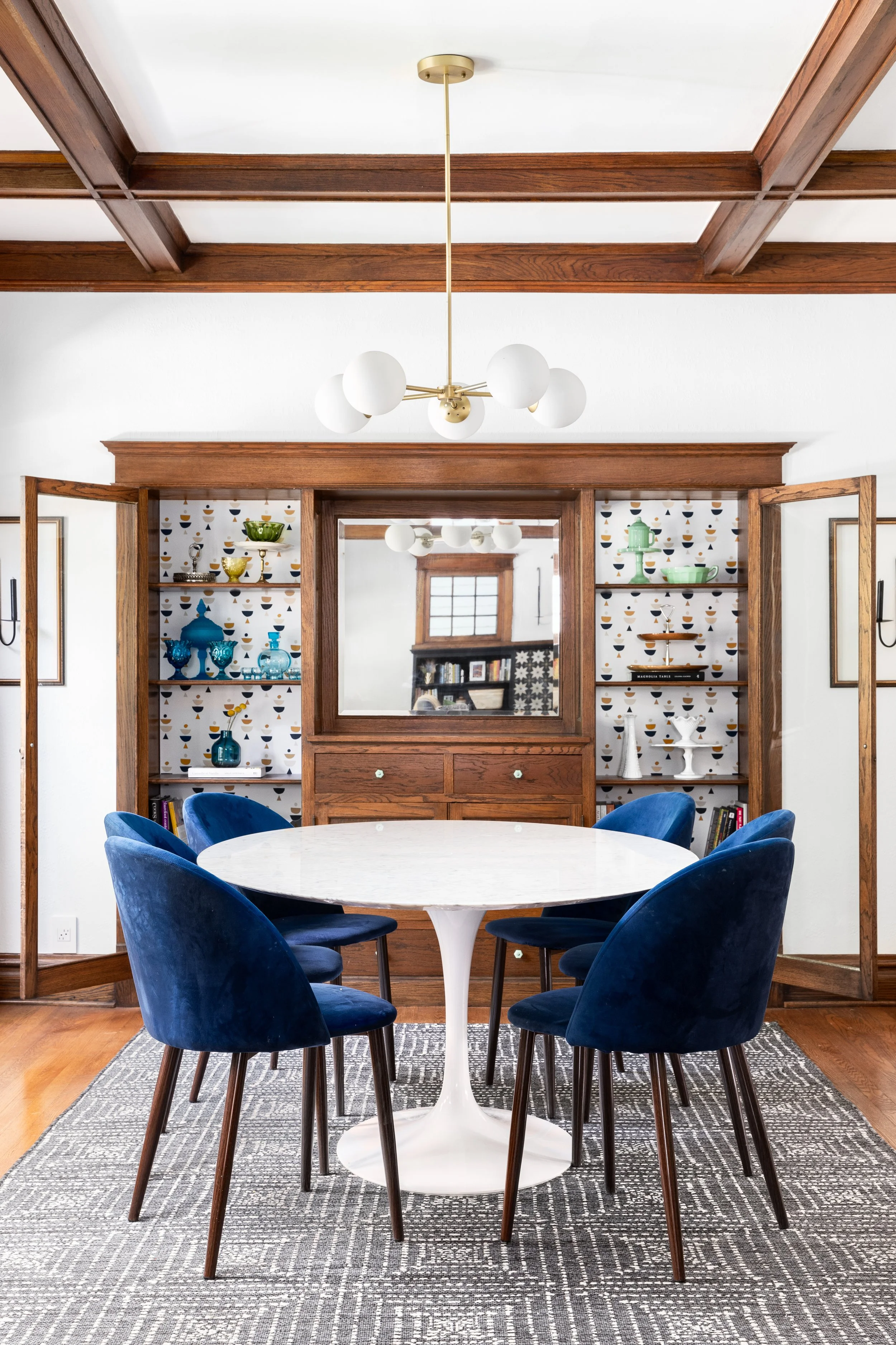 Dining room wood beams white walls blue chairs Saarinen table