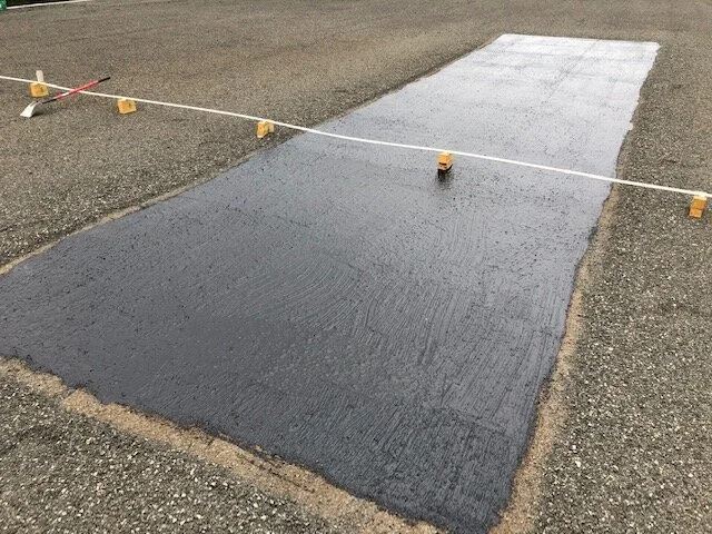 Freshly poured concrete pathway section with wooden spacers and a string line for leveling, outdoors on gravel.