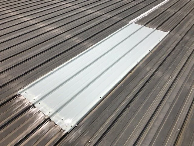White metal vent cover on a gray metal roof.