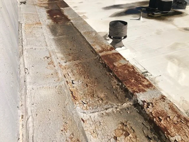 Close-up of a deteriorated and rusted urban rooftop edge with peeling paint and rust stains.
