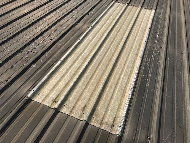 Close-up of a section of a metal roof with a section of corrugated translucent plastic roofing.