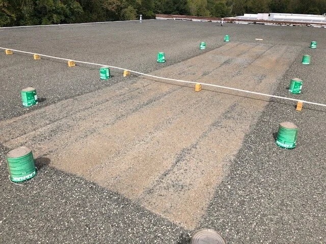 Construction site roof with spray foam insulation and buckets of coating or sealant.