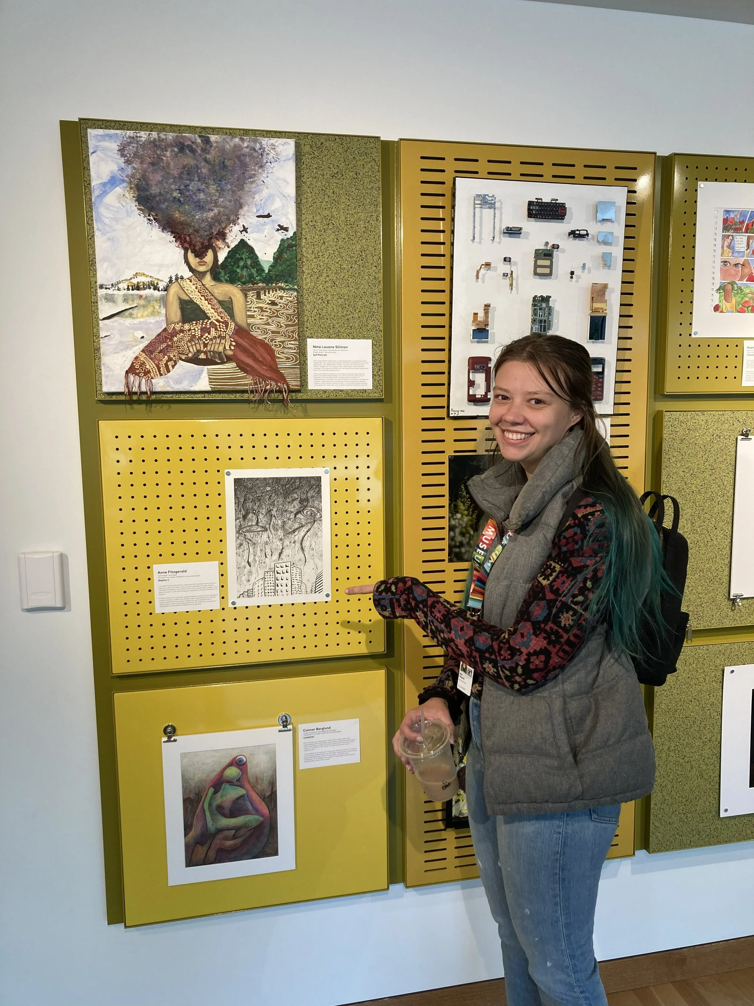 Artist pointing to artwork on yellow art gallery wall