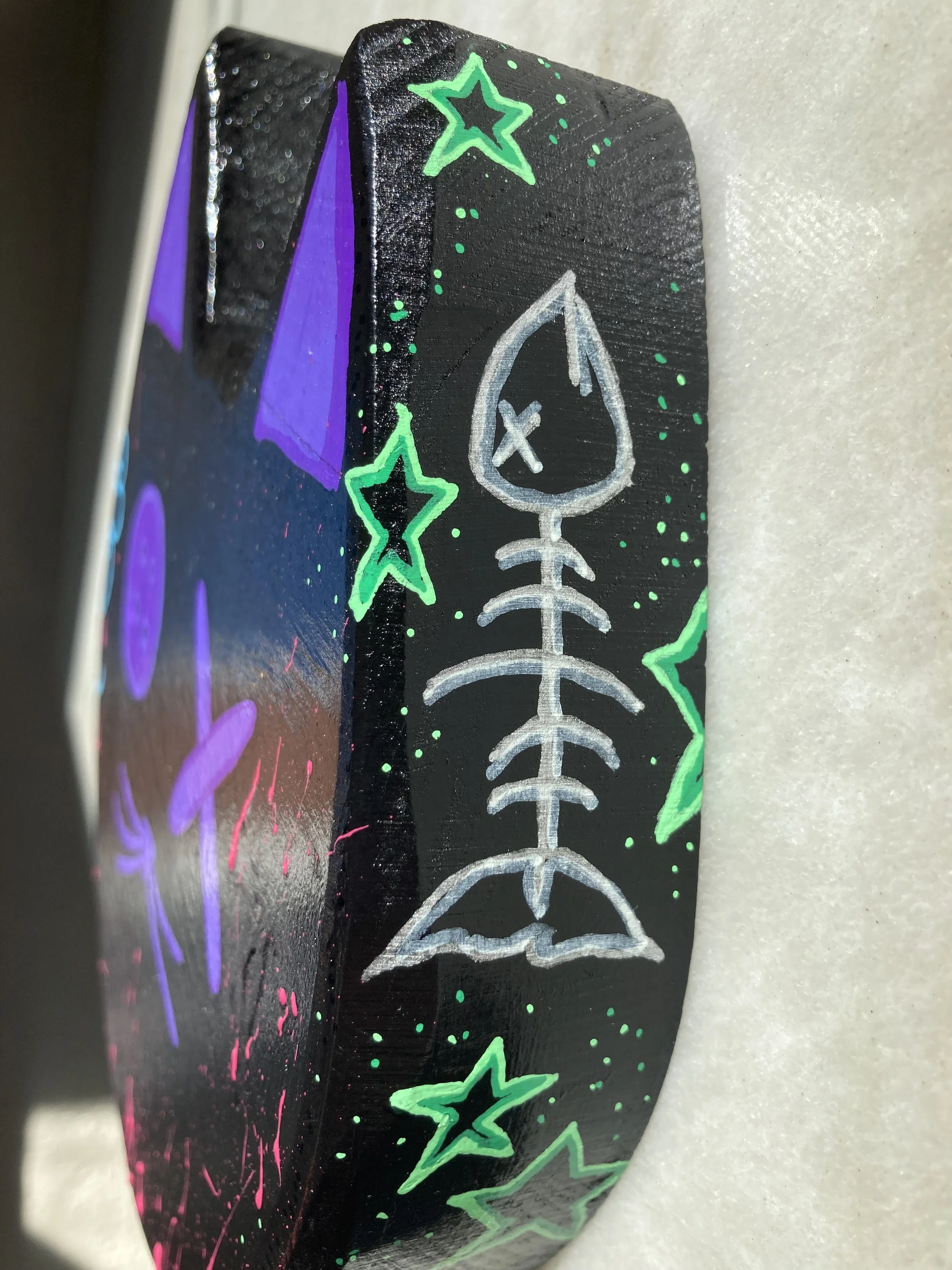 Painted wood cat head art, focused on fish bone and green star detail.