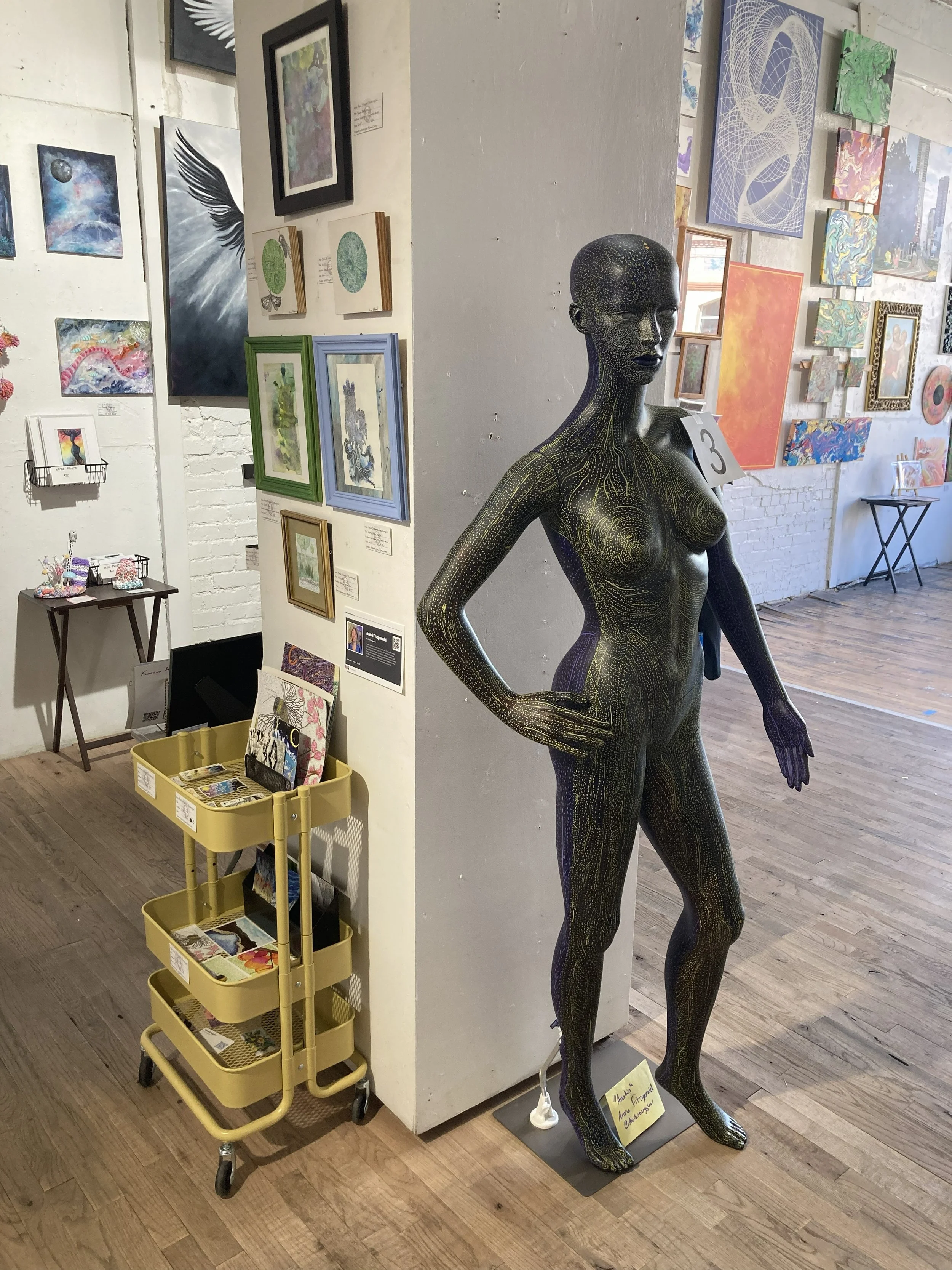 Mannequin covered with painted dots. It in in an art gallery.