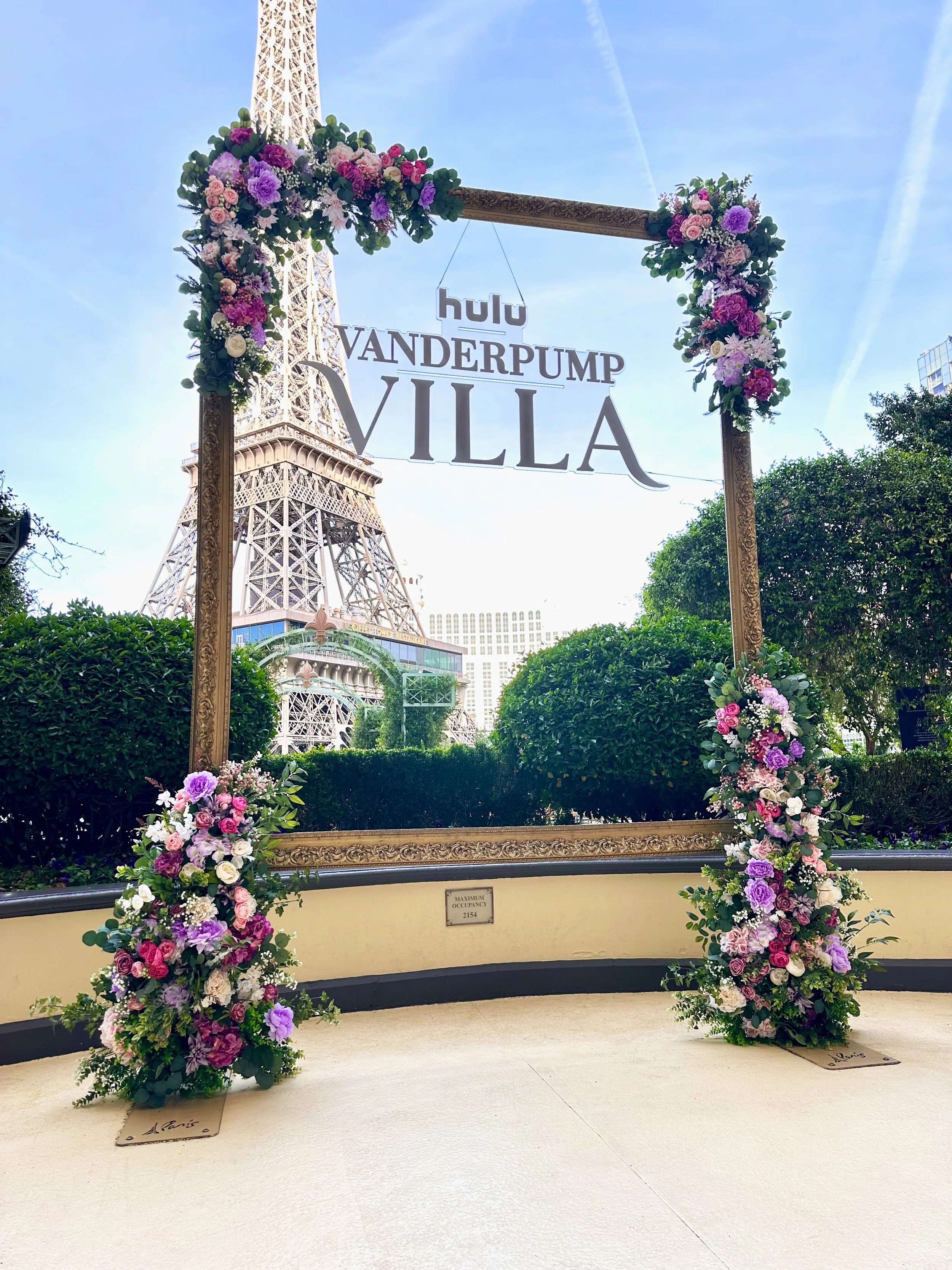 Purple and pink flowers on all corners of large gold picture frame in front of the Eiffel Tower at the Paris Las Vegas Hotel and Casino