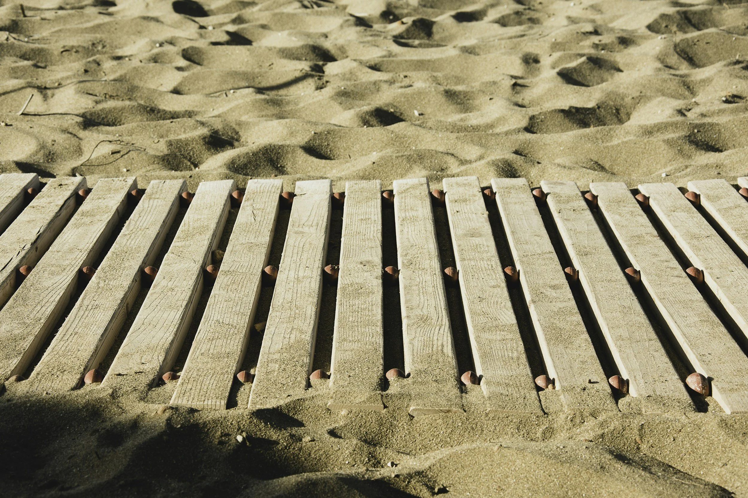Wooden pathway through sand representing the healing journey in grief therapy and bereavement counseling in Sarasota.