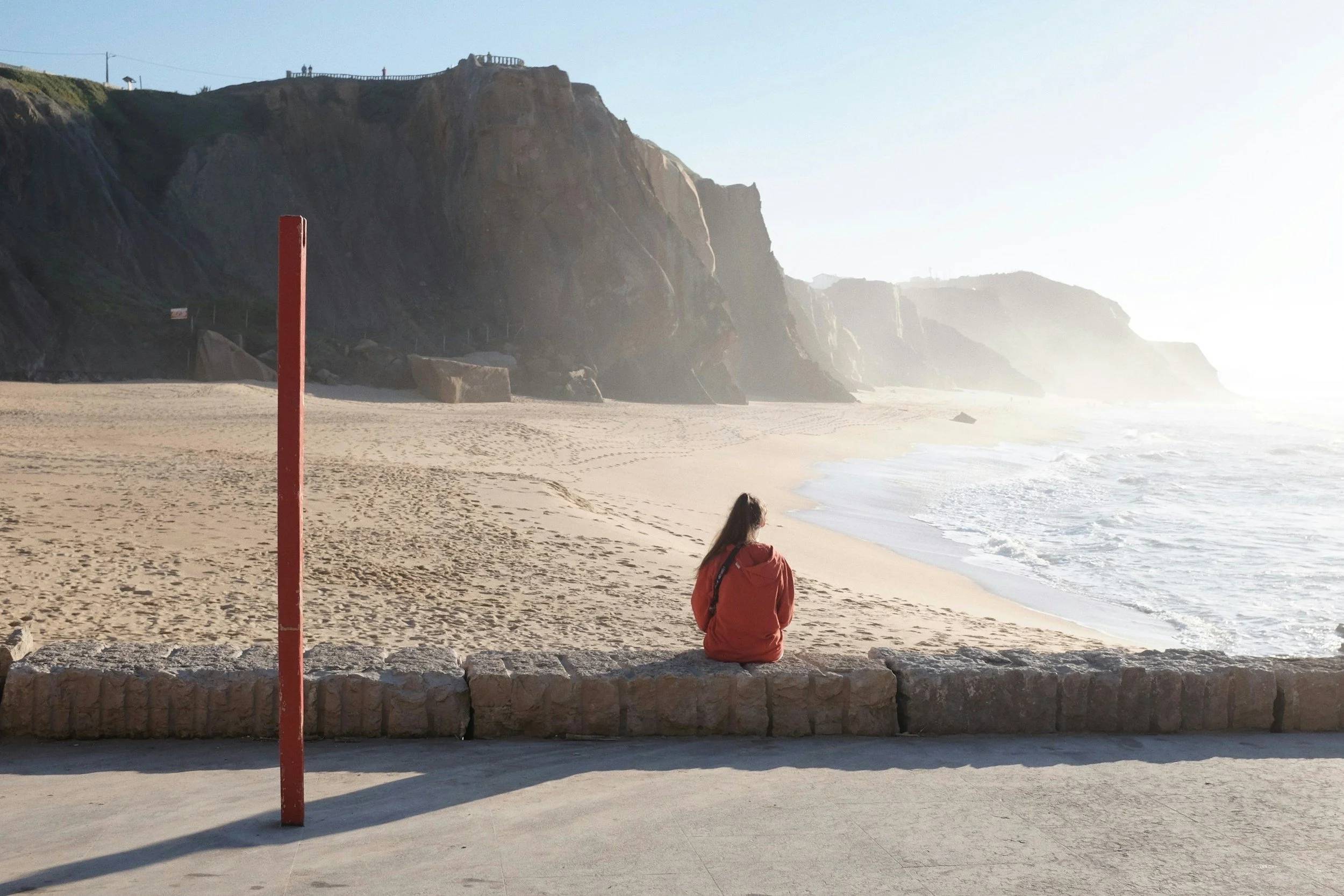 Teen sitting alone on a beach representing the emotional isolation addressed in teen anger management therapy at It Begins Within Healing Center