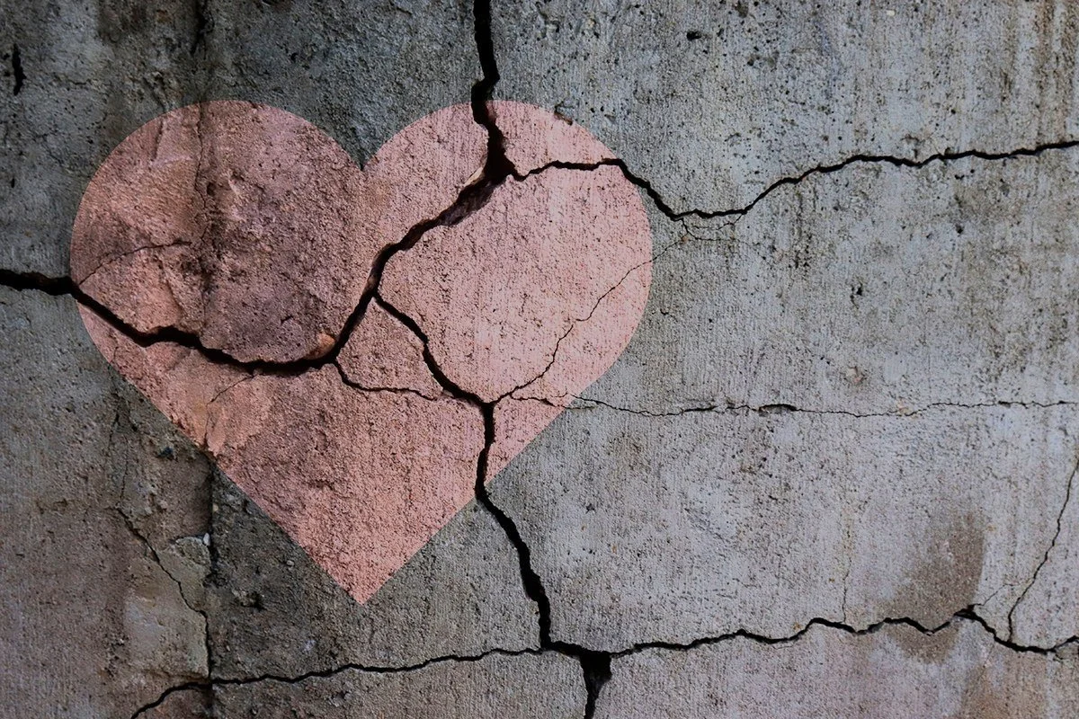 Broken heart on cracked concrete representing betrayal and relationship trauma