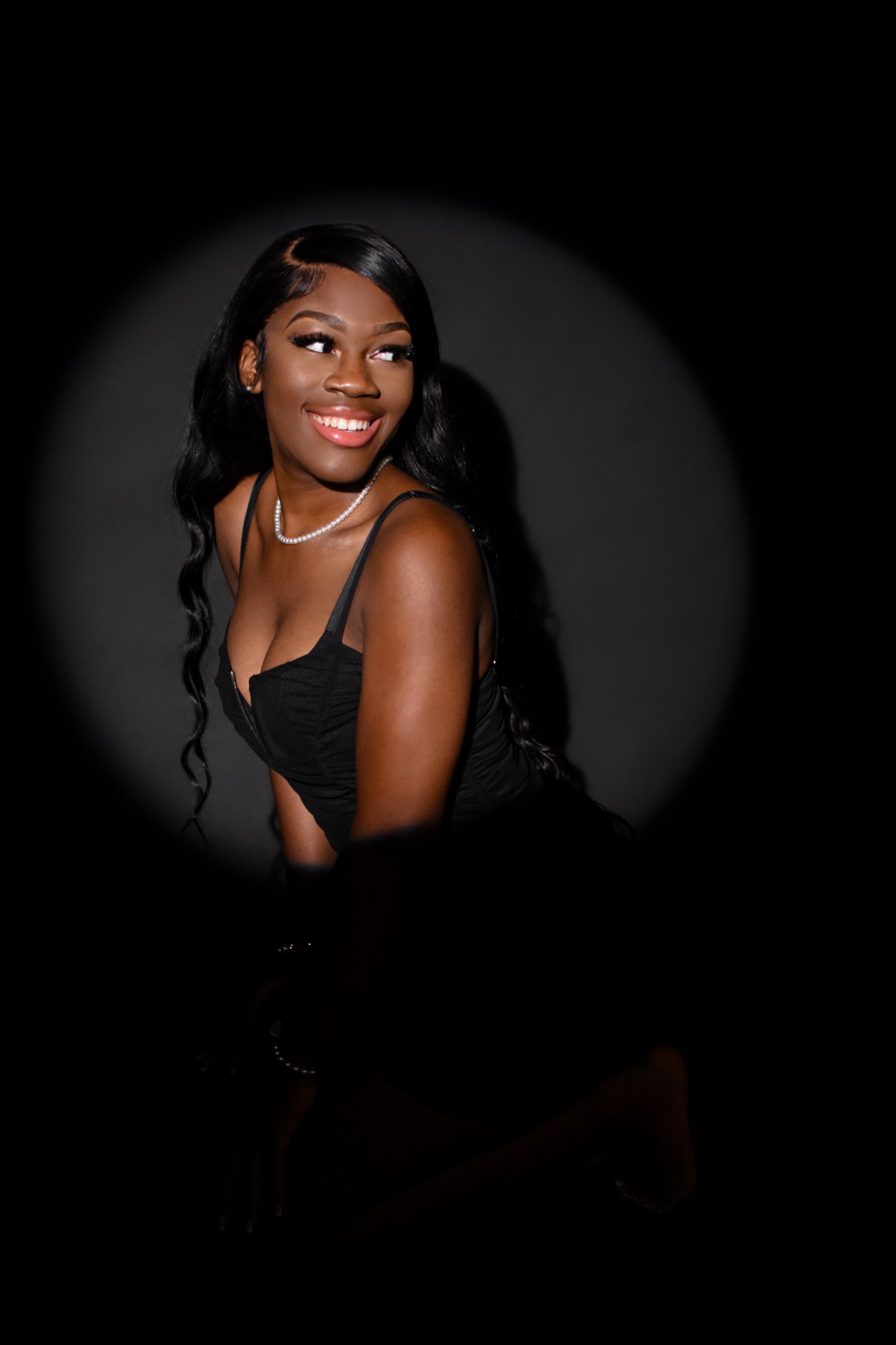 Smiling person wearing a black dress in spotlight